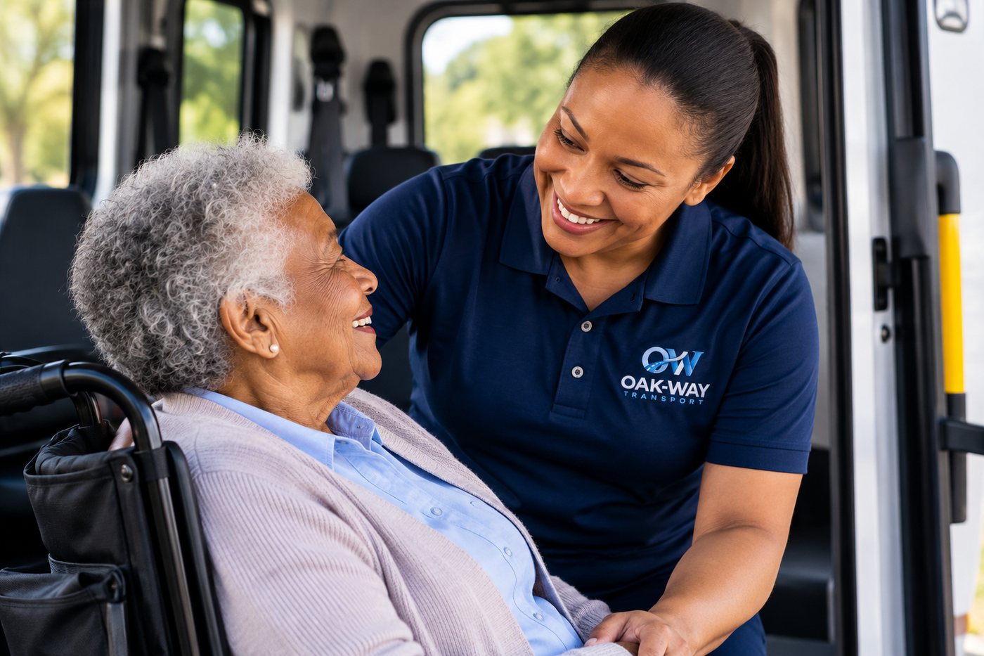 An Oak-Way Transport attendant smiling with a senior passenger seated in a wheelchair at the vehicle door.